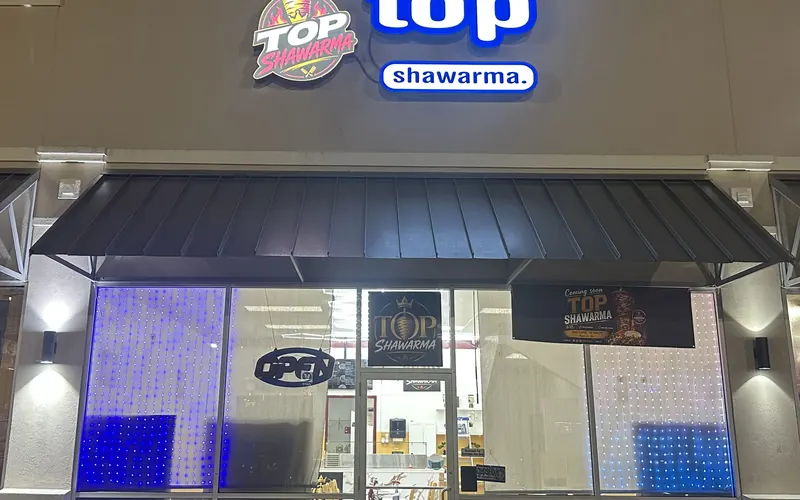 The Top Shawarma storefront on East Texas Street at night, lit sign over the glass door